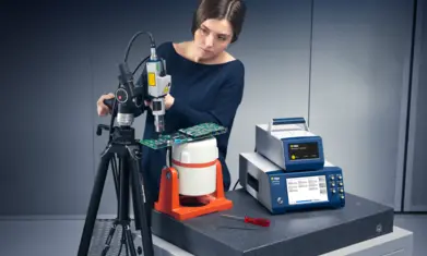 Technician operating Polytec VibroScan laser Doppler vibrometer inspecting vibration on a circuit board for micro-scale analysis.