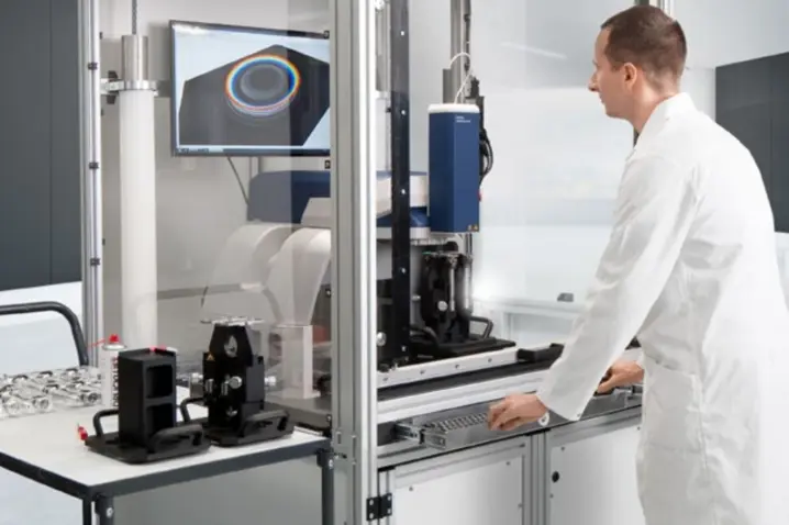 Scientist in white lab coat operating Polytec non-contact surface metrology system for material analysis.
